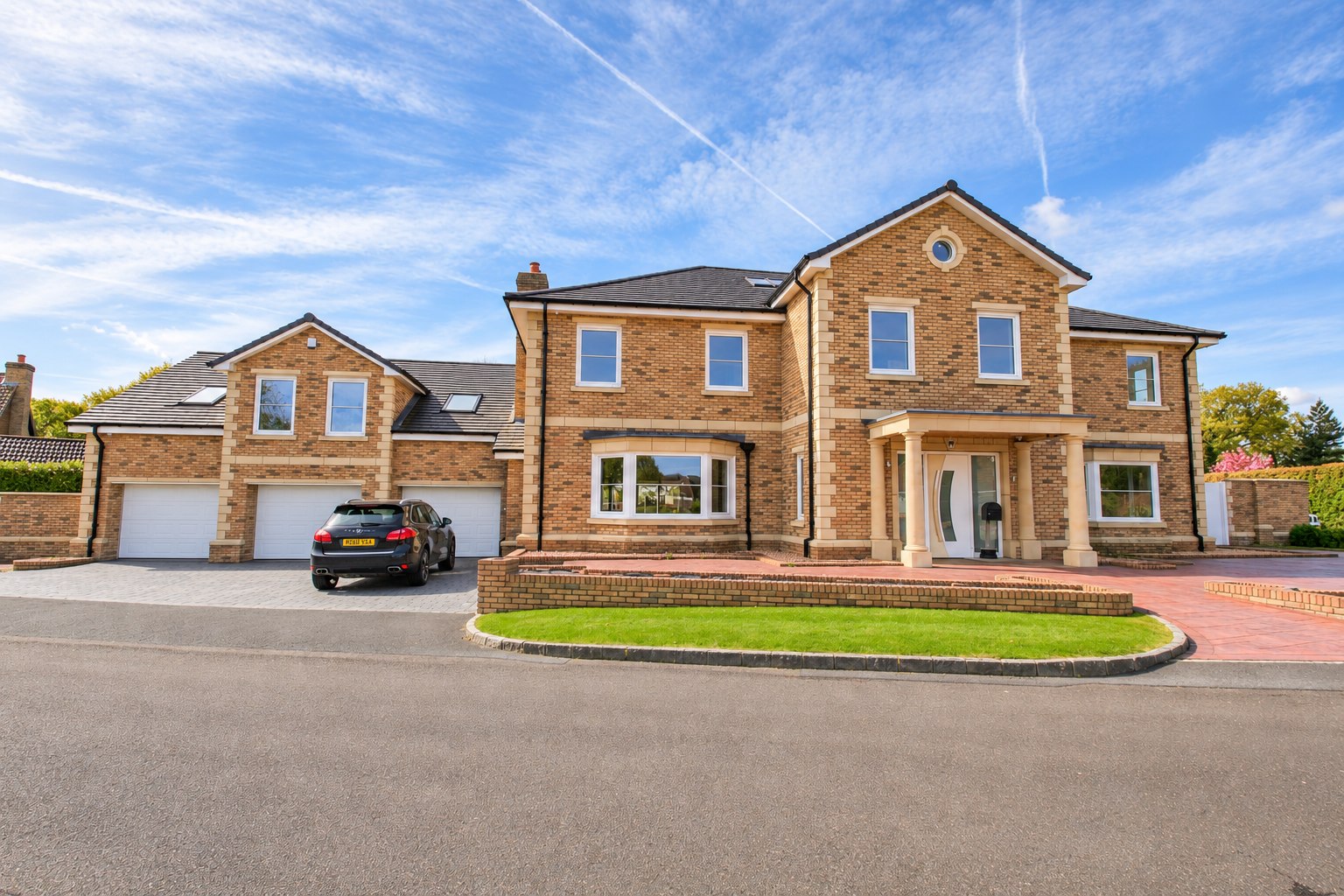 Buff brick detached home with a columned entrance and garages